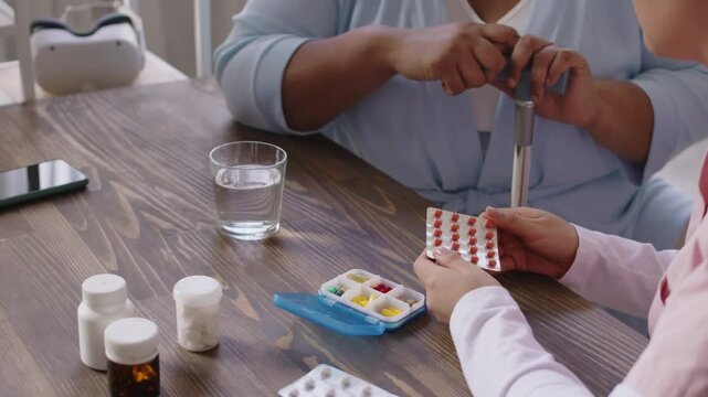 Nurse explaining unrecognisable senior woman with cane how to take daily pills correctly while sitting at desk