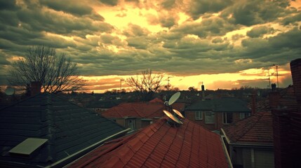 A dramatic sunset casts a warm glow over a cityscape, with clouds casting long shadows over the rooftops.