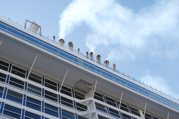 A magnificent cruise ships deck with tall smoke stacks contrasts against a beautiful blue sky