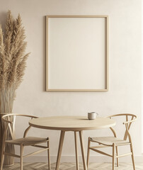 A minimalist dining room with a round table, chairs, and an empty poster frame above. Light beige tones, wood furniture, pampas grass vases, and a coffee cup add a cozy touch.