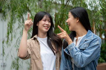 Two attractive Asian female friends are enjoying the view in a lush home garden.