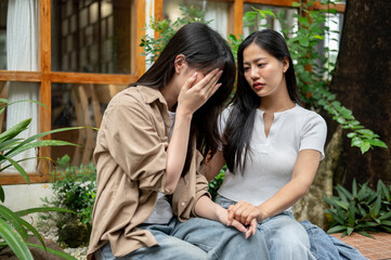 A caring woman is comforting and encouraging her sad friend as they have a conversation in a garden.