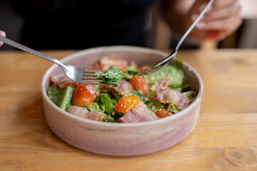 A close-up of a woman savoring a delicious healthy salad with bacon, whether in a restaurant.