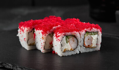 Elegant Sushi Roll with Shrimp and Masago Caviar on a Slate Plate, High Contrast Black Background
