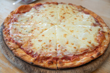 Homemade Greasy Cheese Pizza Ready to Eat closeup on the board on the table.
