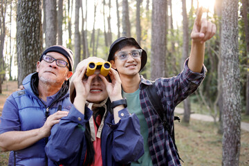 Fototapeta premium Family Members Walking Together in The Forest While Looking Something Through a Binocular