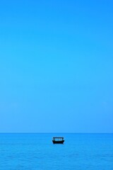 Obraz premium A serene view of a small boat on calm blue waters under a clear sky.