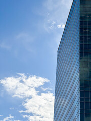 A sleek glass facade reaching towards the clouds ; Geometric patterns in the glass of a skyscraper