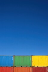 Obraz premium A stack of colorful shipping containers against a clear blue sky.