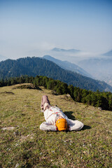 Man sleeping on grass with cap  enjoying natural sun bath in Valley Himachal Pradesh India.