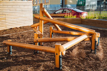 In a lively playground, a sturdy wooden balance beam stands out, providing a fantastic place for children to play, while a vibrant red car nearby captures the essence of outdoor fun and joy