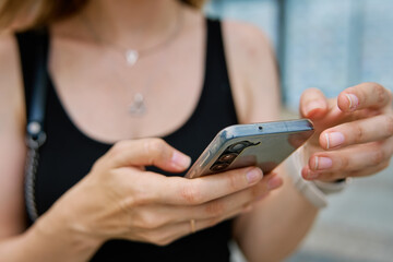 Woman holding smartphone in hands at city street. Female tourist texting on her cell phone outdoors.