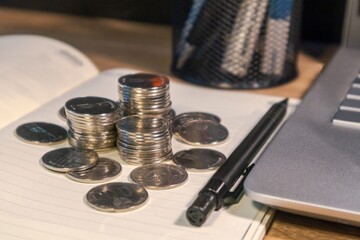 Stack of coins on a book on a wooden work table