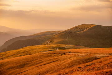 Sunset on Romania Transalpina road with many serpentines crossing forest in  Carpathian mountains. Mountains forest trees with road in Parang mountains