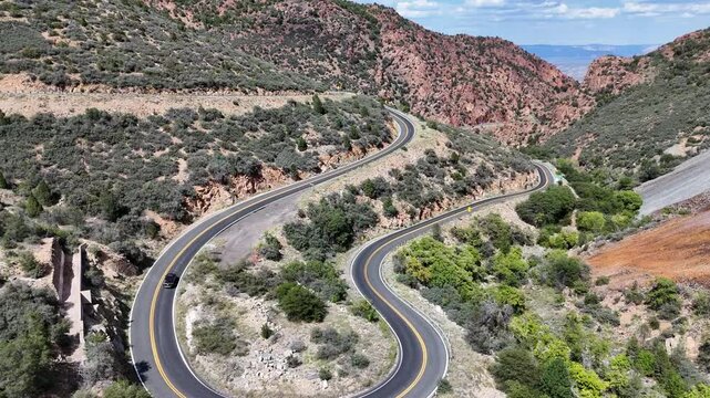 Aerial View of an SUV Driving a Hairpin turn on a Winding Mountain Road on a Summer Day. Highway 89A on the way to Jerome, Arizona