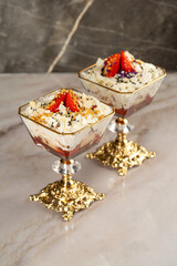 Glass ice-cream bowls with strawberries and cream on black and white background