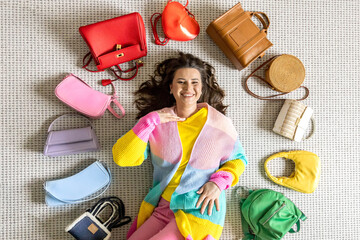 A young beautiful girl lies on the floor in the dressing room, surrounded by many fashionable