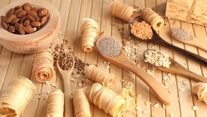 Wooden spoons filled with chia seeds, lentils, oats, buckwheat alongside almond bowl Eco-friendly...