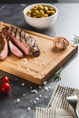 Sliced grilled steak on board with vegetables
