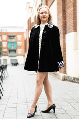 Obraz premium Happy woman in stylish dress walks along cobblestone street
