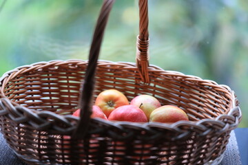 A fruit basket filled with fresh apples placed on a wooden table.