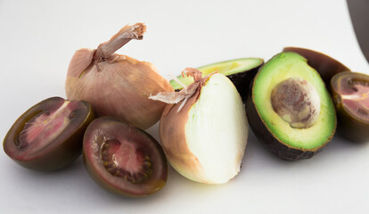 Vegetables black tomatoes, avocado and onions on white background
