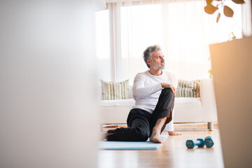 Handsome man exercising at home on gym mat. doing yoga. Routine home workout for a middle-aged man.
