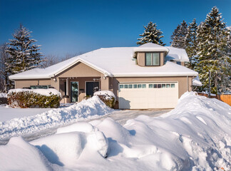 Snowdrifts cleared from driveway of modern single family home 