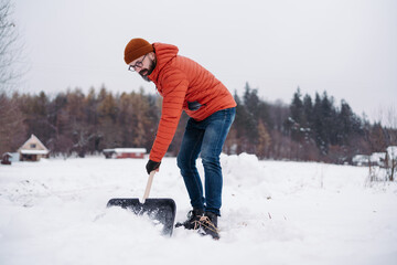 Man shoveling snow with shovel, cleaning driveway in front of the house. Scooping and throwing...