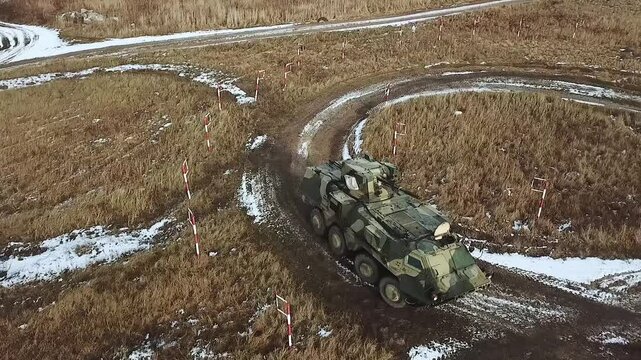 Armored personnel carrier Bucephalus. Armored wheeled vehicles on exercises in Ukraine. Soldiers march at background. Training track at a military training ground.