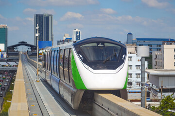 Monorail tram in passing street arrives at the station with passengers
