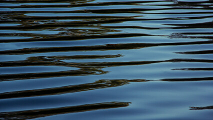 Dark blue lake water with reflection and iridescent patterns