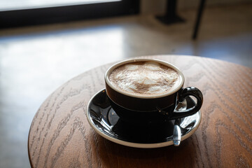 Hot coffee latte with latte art milk foam in cup mug on wood desk on top view. As breakfast In a coffee shop at the cafe,during business work concept,vintage style