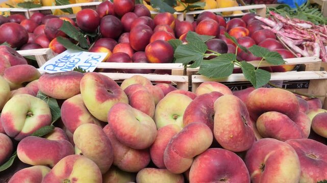 A display of flat peaches and red apples at an Italian market, showcasing the variety and quality of fresh produce in Italy's culinary tradition.