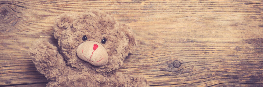 Brown teddy bear over wooden background