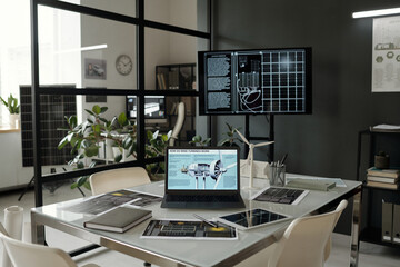 Laptop with explanation of wind turbine work on screen standing in the center of workplace with documents