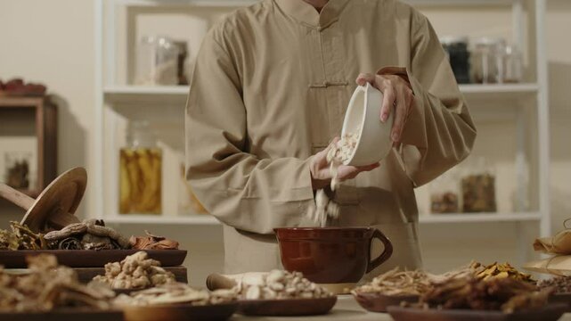 A video sample set in a traditional medicine room features an herbalist pouring Angelica sinensis into a large brown bowl placed on a table alongside other herbal ingredients.