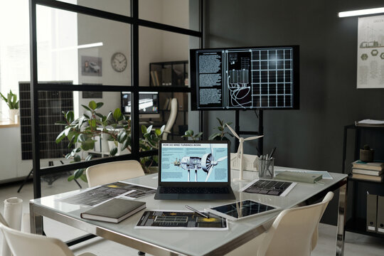 Laptop with explanation of wind turbine work on screen standing in the center of workplace with documents