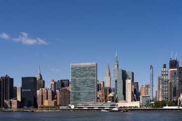 Obraz premium New York City skyline featuring the United Nations headquarters and surrounding skyscrapers on a clear day.