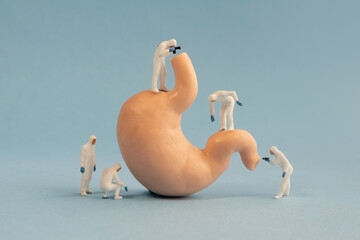 Miniature medical personnel checking the condition of human stomach organs. 