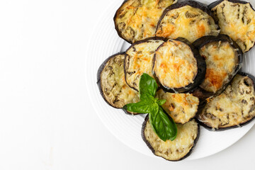 Baked, cheesy eggplant medallions garnished with fresh basil on a white plate, ideal for healthy eating and vegetarian diets
