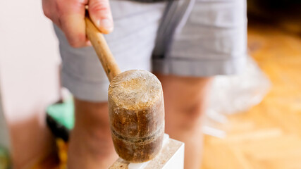 Close-up of a person using a wooden mallet for home renovation, symbolizing DIY carpentry projects and craftsmanship
