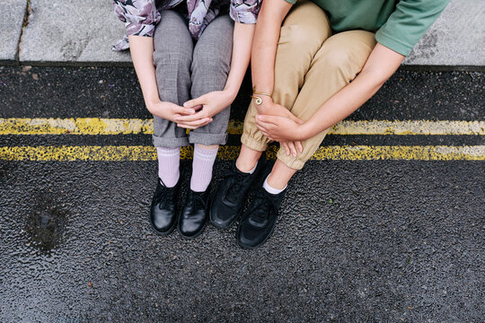 Young lesbian couple sitting on road