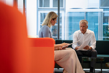 Senior businessman discussing over documents in office lobby