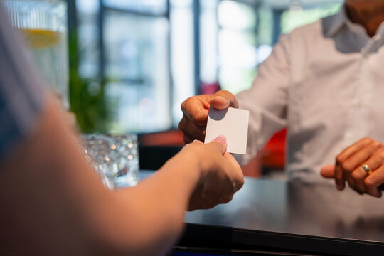 Receptionist giving room cardkey to man at reception desk in hotel