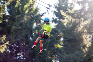 A boy bungee-sliding in the trees in summer