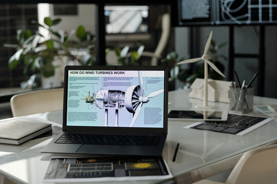 Workplace of modern architect with visual template of windmill turbine on laptop screen in office