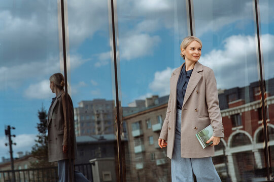 Businesswoman in jacket standing in front of glass wall