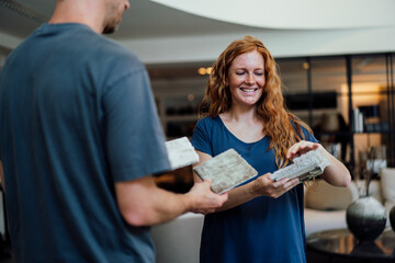 Smiling woman discussing over carpet samples with vendor at store