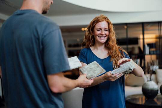 Smiling woman discussing over carpet samples with vendor at store